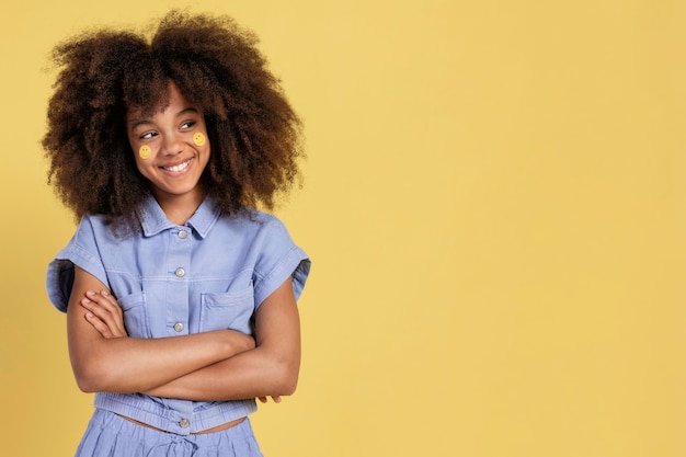 Porträt des jungen entzückenden mädchens, das mit emoji-aufklebern auf ihrem gesicht aufwirft