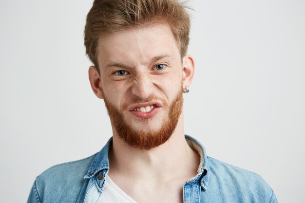 Porträt des jungen fröhlichen fröhlichen Kerls, der lustiges Gesicht täuscht.