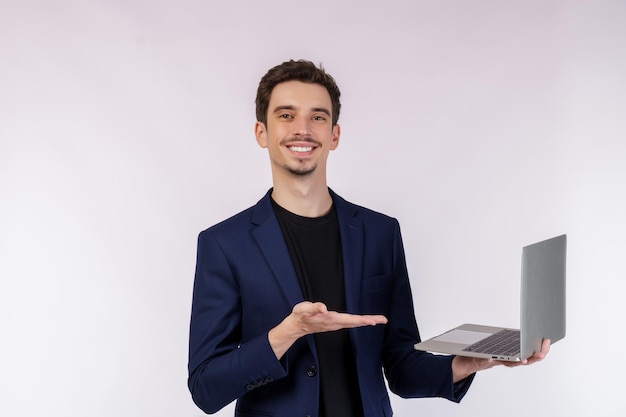 Porträt des jungen gutaussehenden lächelnden Geschäftsmannes, der Laptop in den Händen hält und Webseiten lokalisiert auf weißem Hintergrund tippt und durchsucht