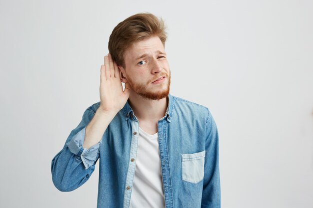 Porträt des jungen gutaussehenden Mannes, der Kamera betrachtet belauscht.