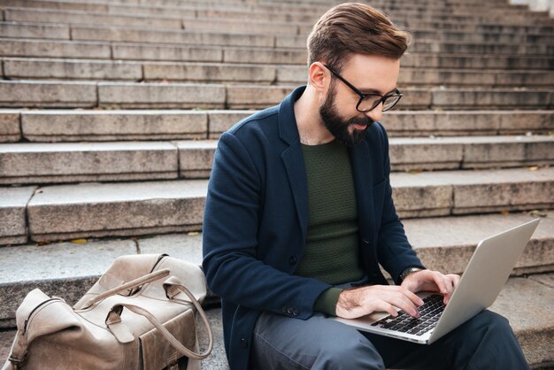 Porträt des jungen gutaussehenden Mannes unter Verwendung des Mobiltelefons