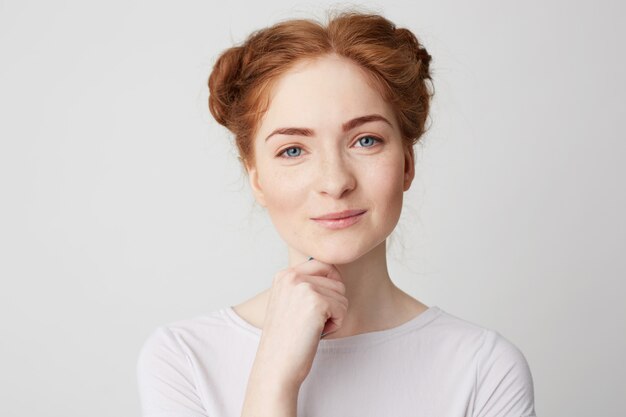 Porträt des jungen hübschen Mädchens mit dem roten Haar lächelnd berührendes Kinn.