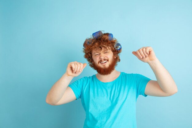 Porträt des jungen kaukasischen Mannes in seiner Schönheitstag- und Hautpflege-Routine. Männliches Model mit natürlichem rotem Haar, das seine Frisur macht, braucht mehr Locken.