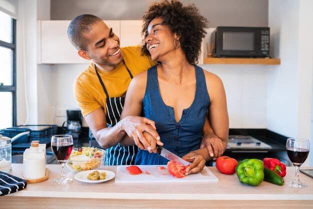 Porträt des jungen lateinischen Paares, das zusammen in der Küche zu Hause kocht. Beziehungs-, Koch- und Lifestyle-Konzept.