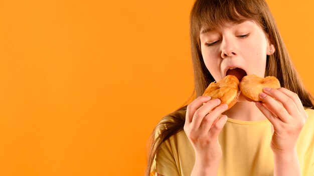 Porträt des jungen Mädchens, das Donuts isst