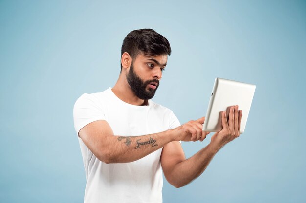 Porträt des jungen Mannes auf blauer Wand mit Tablette