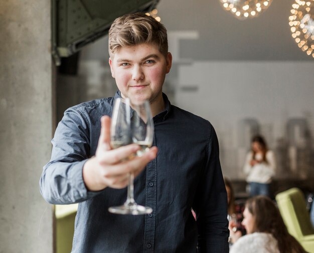 Porträt des jungen Mannes, der ein Glas Wein hält