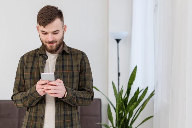 Porträt des jungen Mannes, der Handy hält