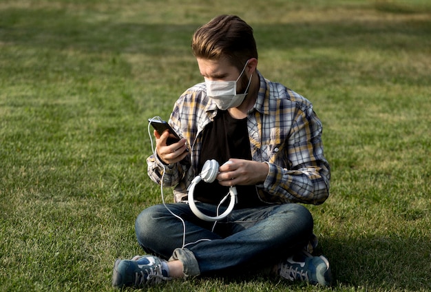 Kostenloses Foto porträt des jungen mannes, der handy im freien durchsucht