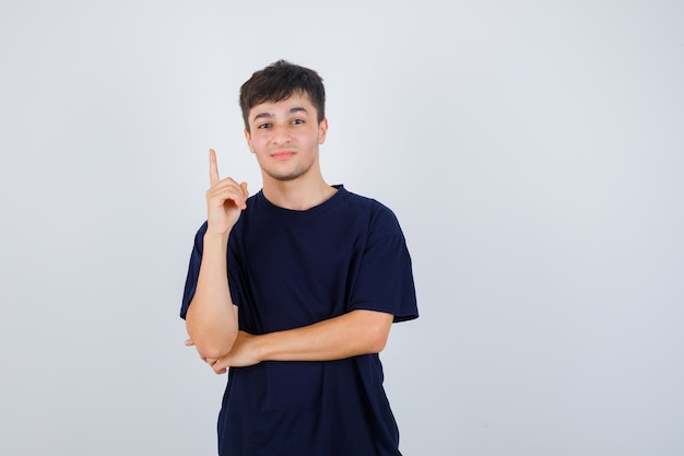 Porträt des jungen Mannes, der im schwarzen T-Shirt oben zeigt und selbstbewusste Vorderansicht schaut