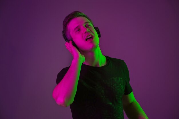 Porträt des jungen Mannes, der Musik mit Neonlichtern hört