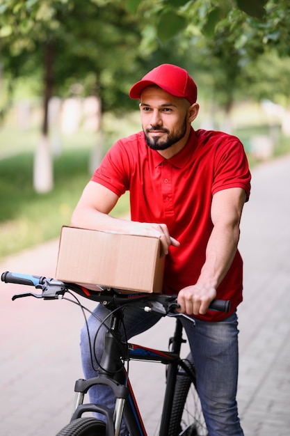 Porträt des jungen Mannes, der Paket auf einem Fahrrad liefert