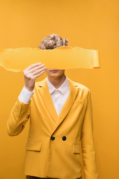 Porträt des jungen Mannes in einer gelben Szene mit heftigem Papier vor Gesicht