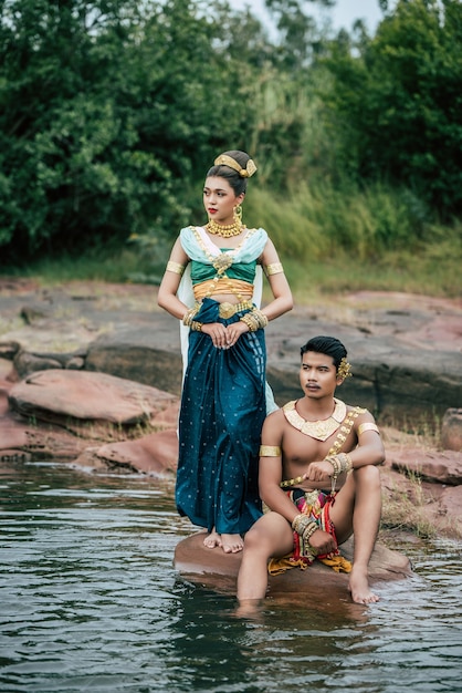 Porträt des jungen mannes und der frau, die schöne traditionelle kostümhaltung in der natur in thailand tragen