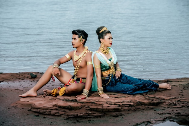 Kostenloses Foto porträt des jungen mannes und der frau, die schöne traditionelle kostümhaltung in der natur in thailand tragen