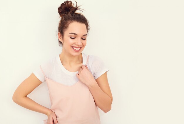 Porträt des jungen schönen Brunettefrauen-Mädchenmodells mit nacktem Make-up im bunten Sommerrosahippie kleidet die Aufstellung nahe Wand. glücklich aussehend