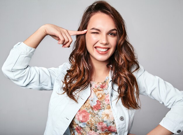 Porträt des jungen stilvollen lachenden Modells in der bunten lässigen Sommerkleidung mit natürlichem Make-up auf Grau