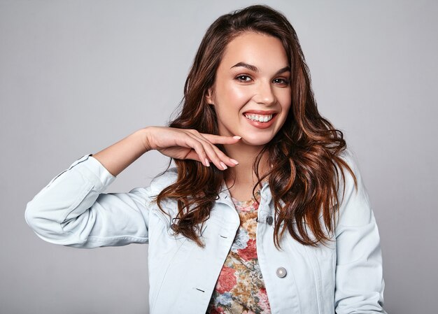 Porträt des jungen stilvollen lachenden Modells in der bunten lässigen Sommerkleidung mit natürlichem Make-up auf Grau