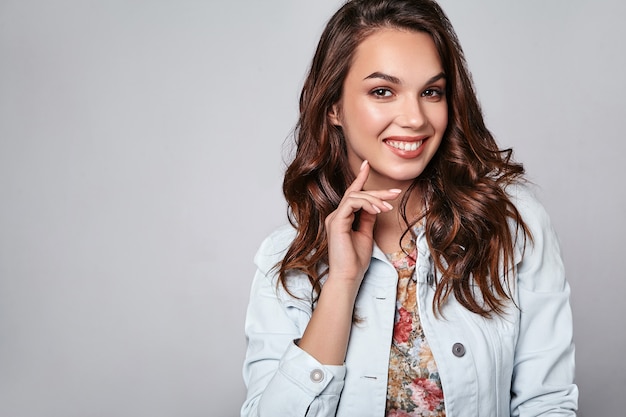 Porträt des jungen stilvollen lachenden Modells in der bunten lässigen Sommerkleidung mit natürlichem Make-up auf Grau