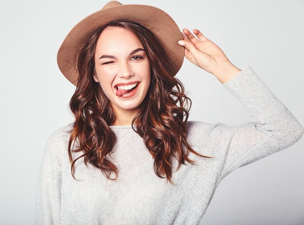 Porträt des jungen stilvollen lachenden Modells in der grauen lässigen Sommerkleidung im braunen Hut mit natürlichem Make-up