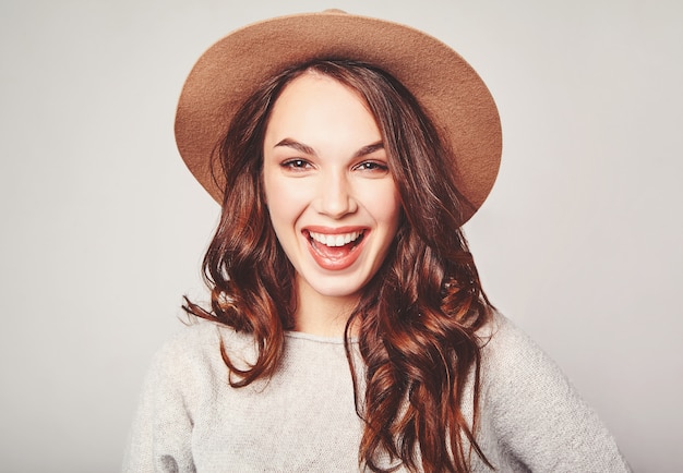 Porträt des jungen stilvollen lachenden Modells in der grauen lässigen Sommerkleidung im braunen Hut mit natürlichem Make-up