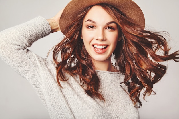 Porträt des jungen stilvollen lachenden Modells in der grauen lässigen Sommerkleidung im braunen Hut mit natürlichem Make-up