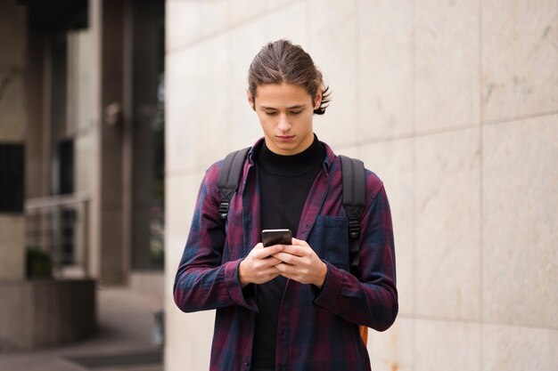 Kostenloses Foto porträt des jungen touristen sein telefon überprüfend