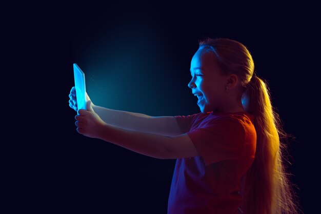 Porträt des kaukasischen Mädchens lokalisiert auf Dunkelheit im Neonlicht