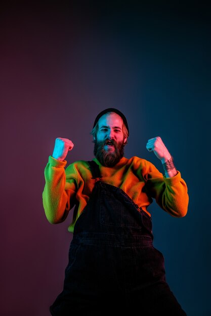 Porträt des kaukasischen Mannes lokalisiert auf Gradientenstudiohintergrund im Neonlicht