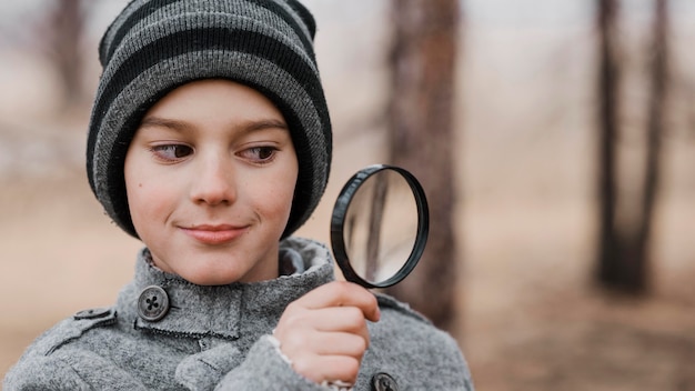 Kostenloses Foto porträt des kleinen jungen, der durch eine lupe mit kopienraum schaut