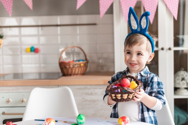 Porträt des kleinen Jungen, der einen Korb mit Ostereiern hält