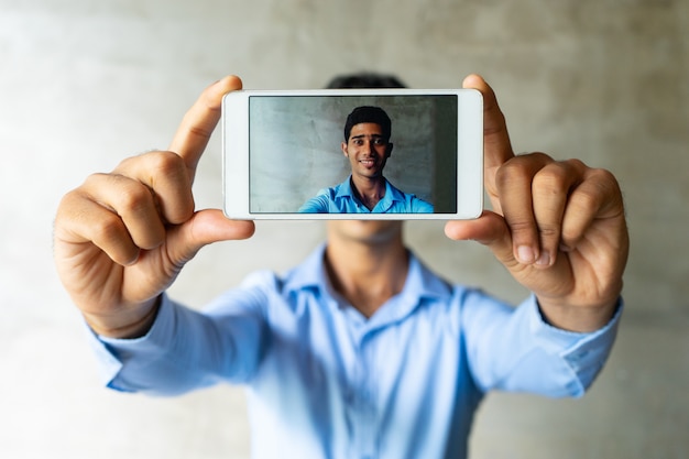 Porträt des lächelnden Geschäftsmannes selfie mit Smartphone nehmend.