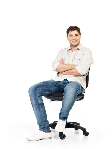 Porträt des lächelnden glücklichen Mannes sitzt auf dem Bürostuhl lokalisiert auf Weiß.