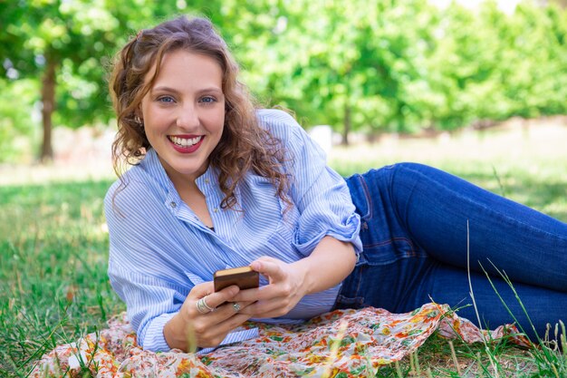 Porträt des lächelnden hübschen Mädchens, das mobiles Internet verwendet