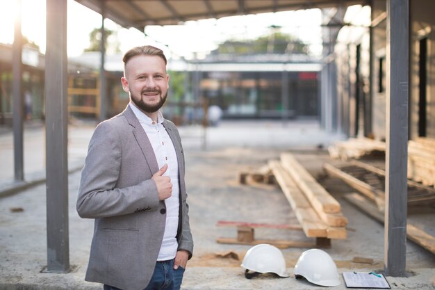 Porträt des lächelnden jungen Architektenmannes, der Daumen herauf die Geste betrachtet Kamera zeigt