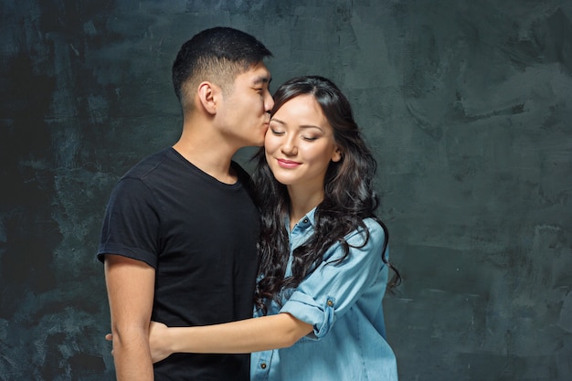 Porträt des lächelnden koreanischen Paares auf einem grauen Studiohintergrund