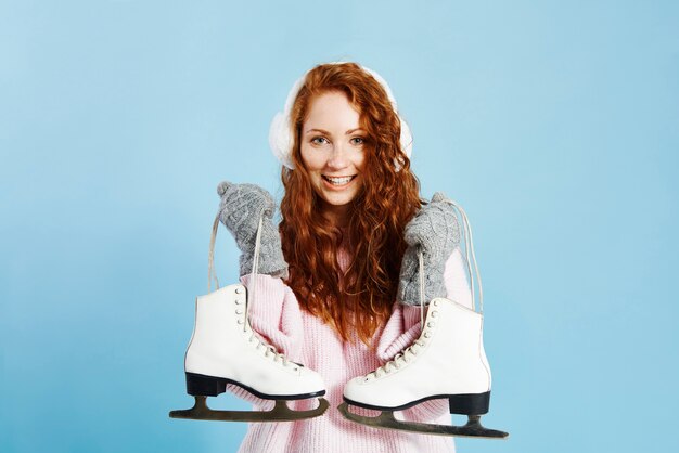 Porträt des lächelnden Mädchens, das Schlittschuhe hält
