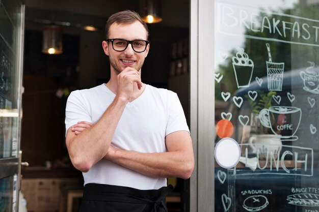 Porträt des lächelnden männlichen Kellners außerhalb des Cafés