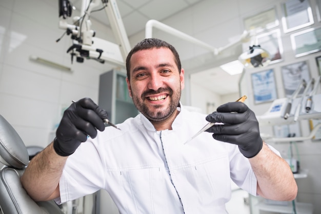 Porträt des lächelnden männlichen Zahnarztes mit zahnmedizinischen Werkzeugen