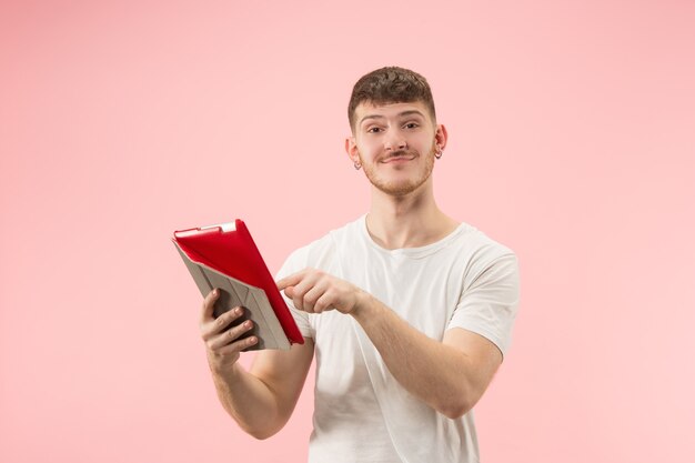 Porträt des lächelnden Mannes, der auf Laptop mit leerem Bildschirm lokalisiert auf rosa Studio zeigt