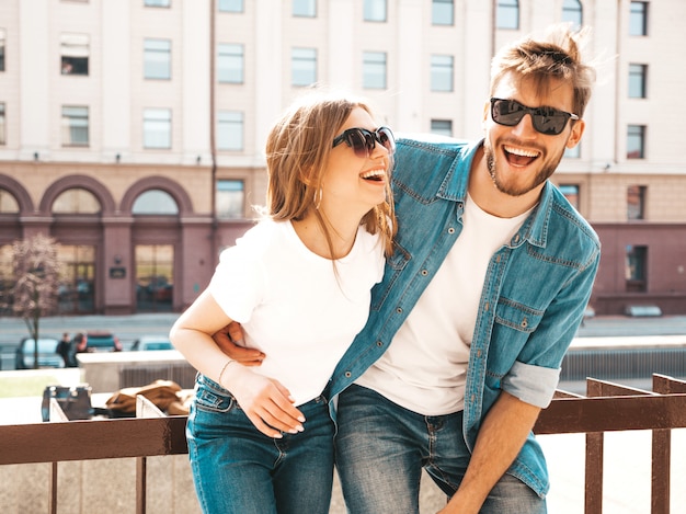 Porträt des lächelnden schönen Mädchens und ihres hübschen Freundes in der zufälligen Sommerkleidung und -sonnenbrille. . Umarmen