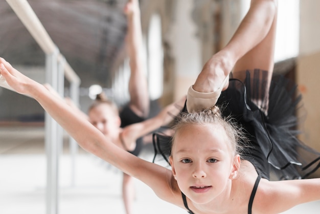 Kostenloses Foto porträt des mädchens mit ihrem bein, das oben während einer ballettklasse übt