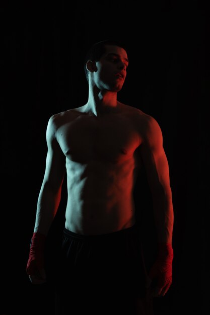 Porträt des männlichen Boxers, der im roten und weißen Licht aufwirft