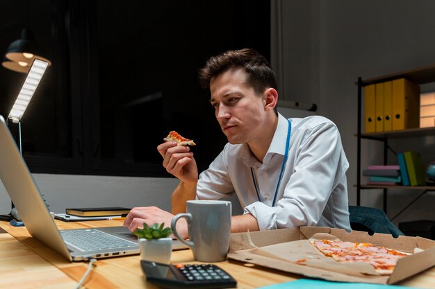 Porträt des Mannes, der einen Snack während der Arbeit von zu Hause aus hat