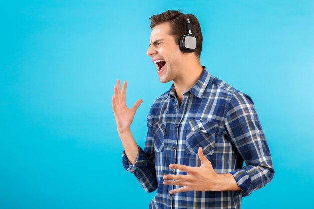 Porträt des Mannes, der Musik auf kabellosen Kopfhörern hört, die Spaß auf Blau haben