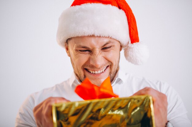 Porträt des Mannes in Sankt-Hut, der Weihnachtsgoldenen Präsentkarton hält