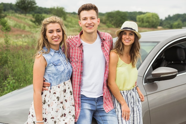 Kostenloses Foto porträt des mannes stehend mit seinen weiblichen freunden nahe dem auto