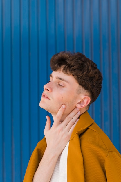 Kostenloses Foto porträt des modernen jungen gegen blaue wand