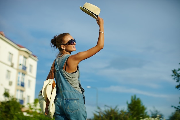 Porträt des netten lustigen jungen stilvollen lächelnden Frauenfrauenmodells im zufälligen modernen Stoff mit perfektem sonnengebadetem Körper draußen im Park im Hut