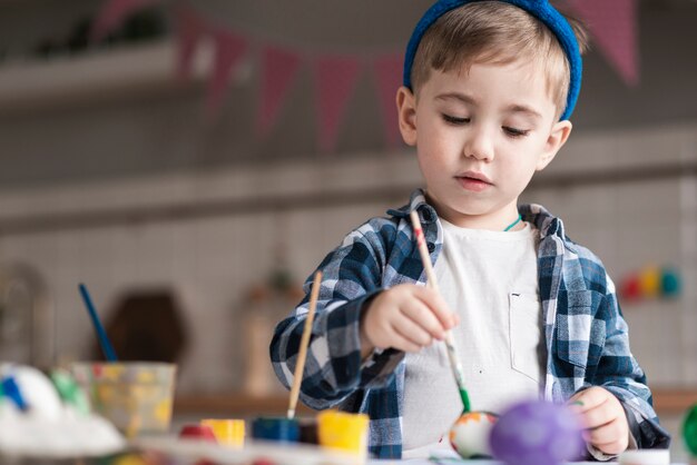 Porträt des niedlichen Jungen, der Eier für Ostern malt